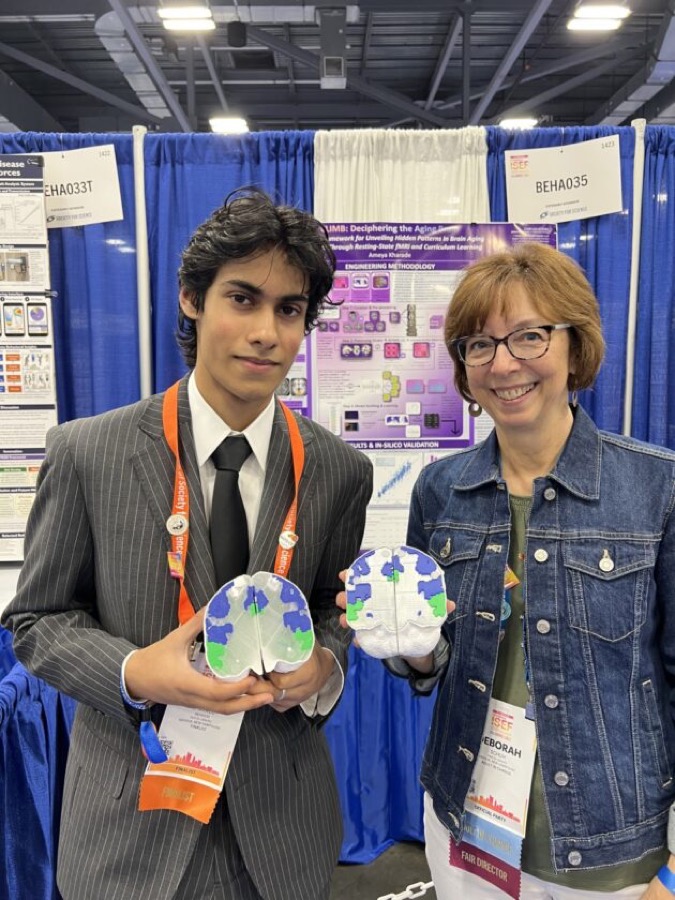 Ameya Kharade holding brain models beside a Regeneron ISEF fair director